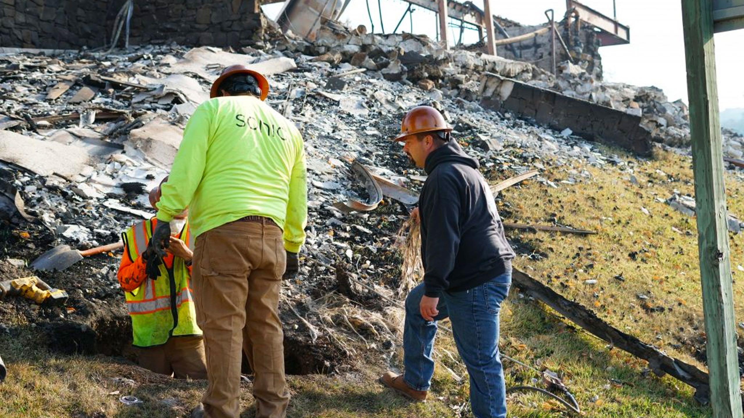 Sonic workers standing over post-fire rubble on the ground.